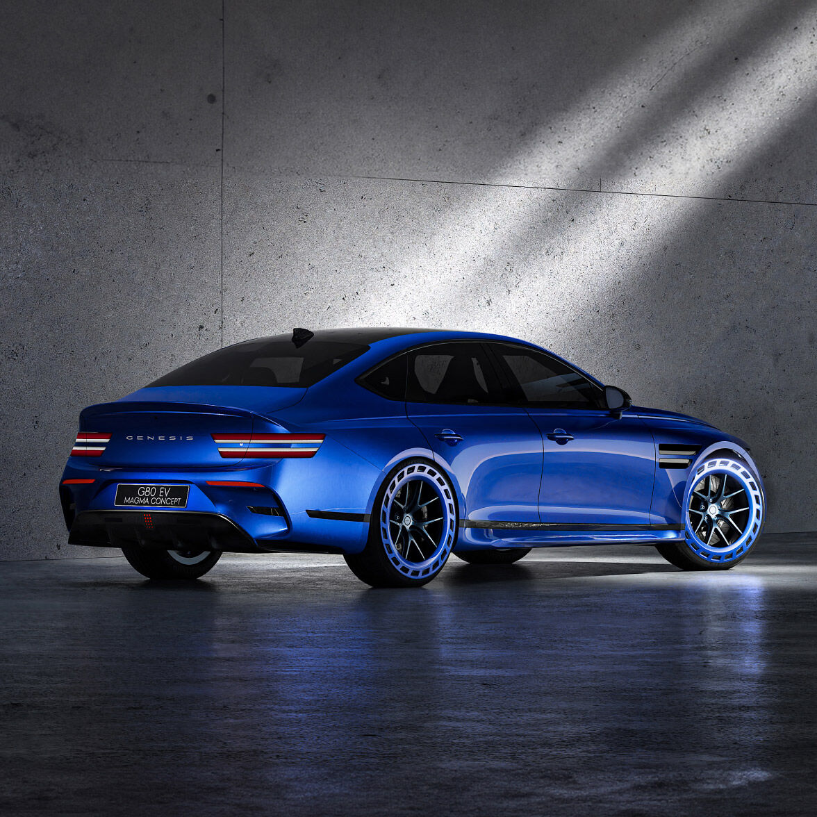 Vision blue two-tone Genesis G80 EV Magma Concept is parked in front of a blue-ish gray background. The floor is concrete.