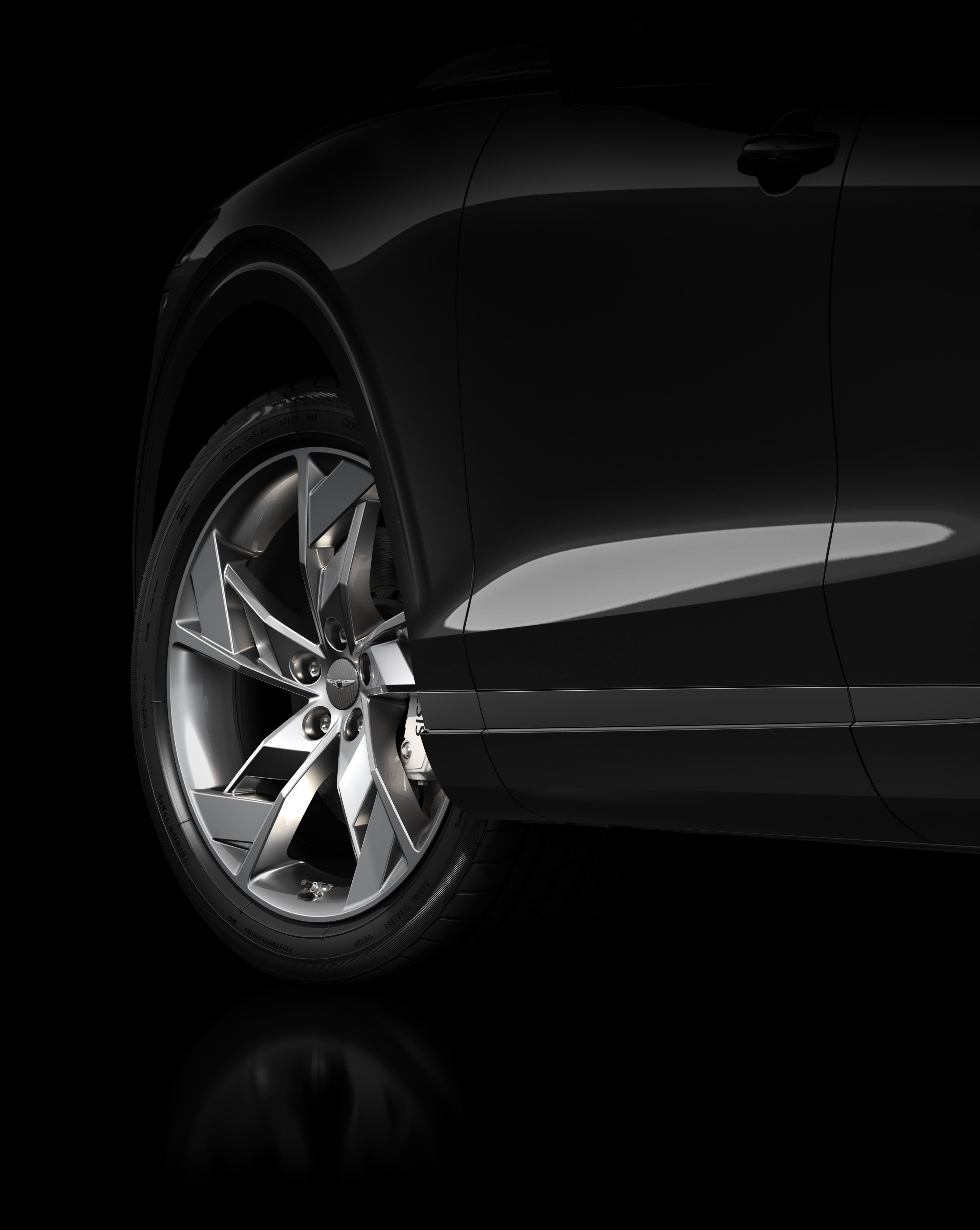 The Electrified GV70’s tire turns to the left on a brown tarmacked road.