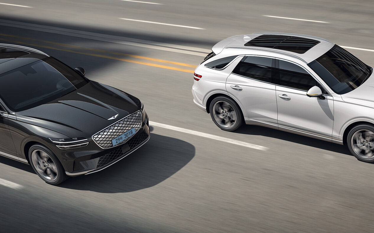 An angled aerial view of the Electrified GV70 overtaking a car on a highway.