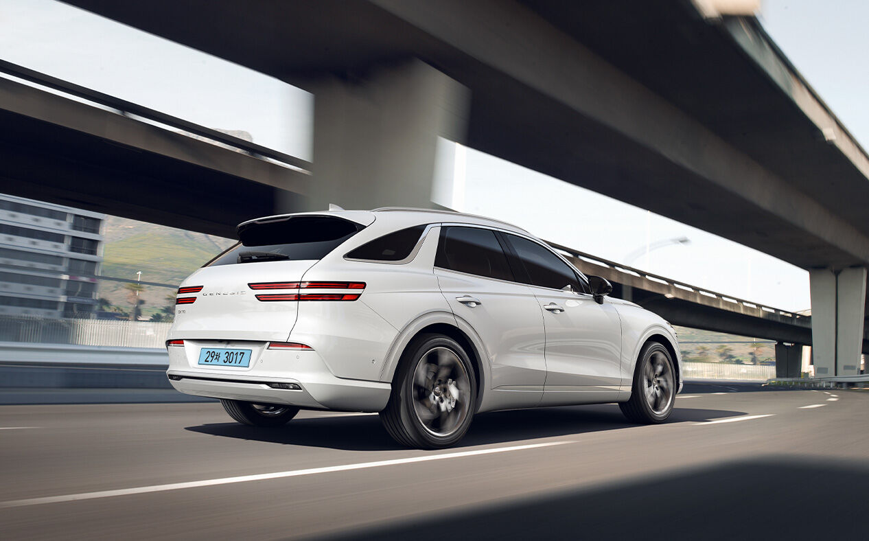 The Electrified GV70 is seen from behind as it drives on the highway.