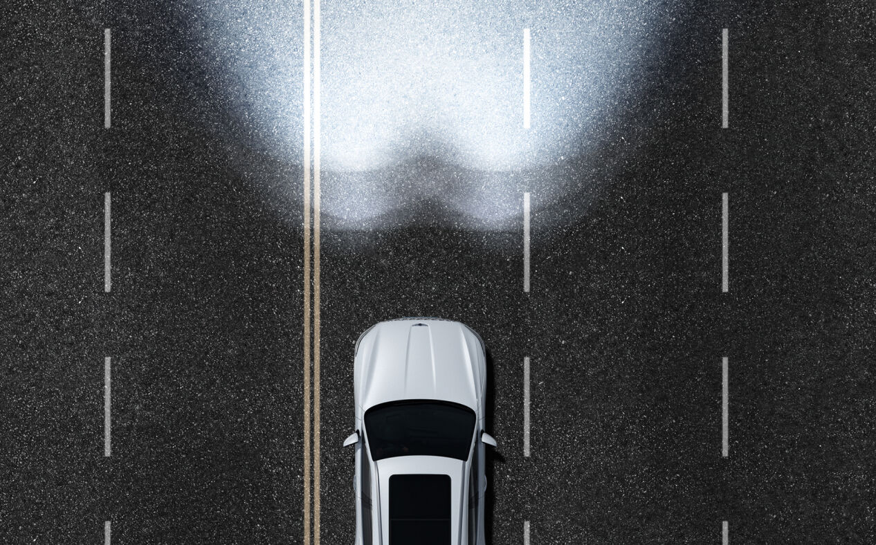 An aerial view of the Electrified GV70 using high beams on the highway.