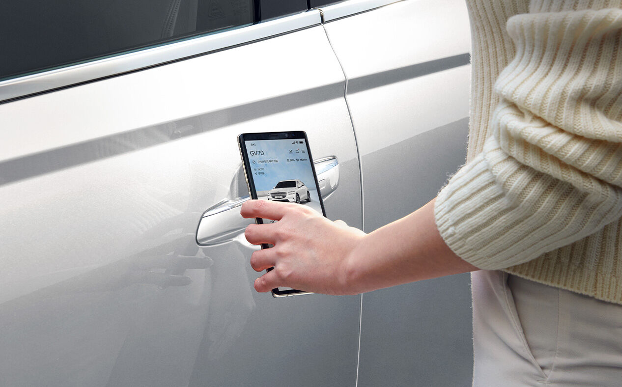 A person’s hand is seen close to the door handle using their smartphone as a digital key.