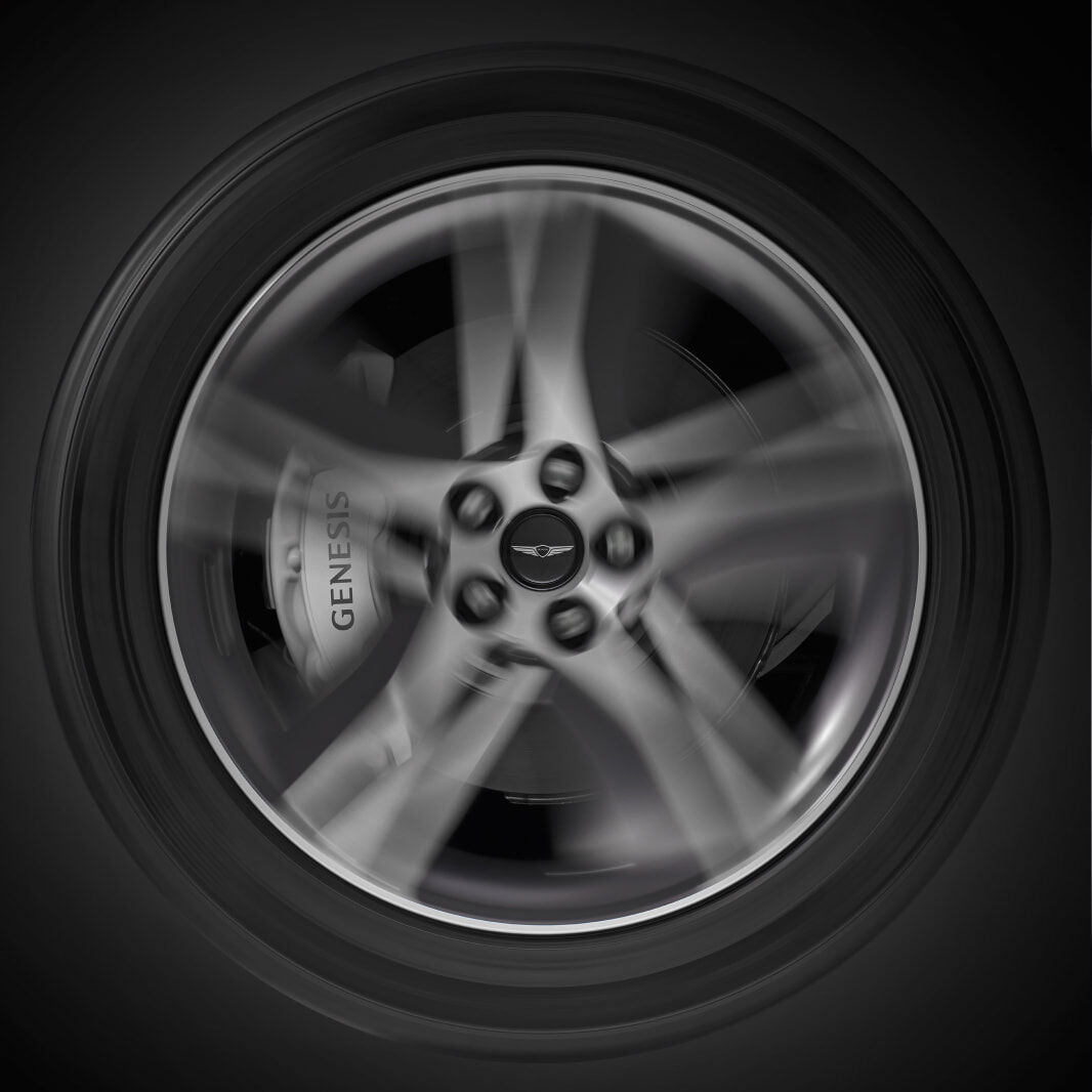 The Genesis logo is clearly displayed in the center of a rapidly spinning tire.