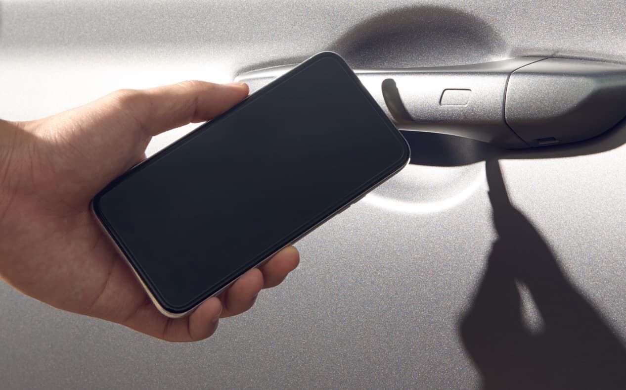 Using the Genesis Digital Key app while holding a smartphone close to the car door.