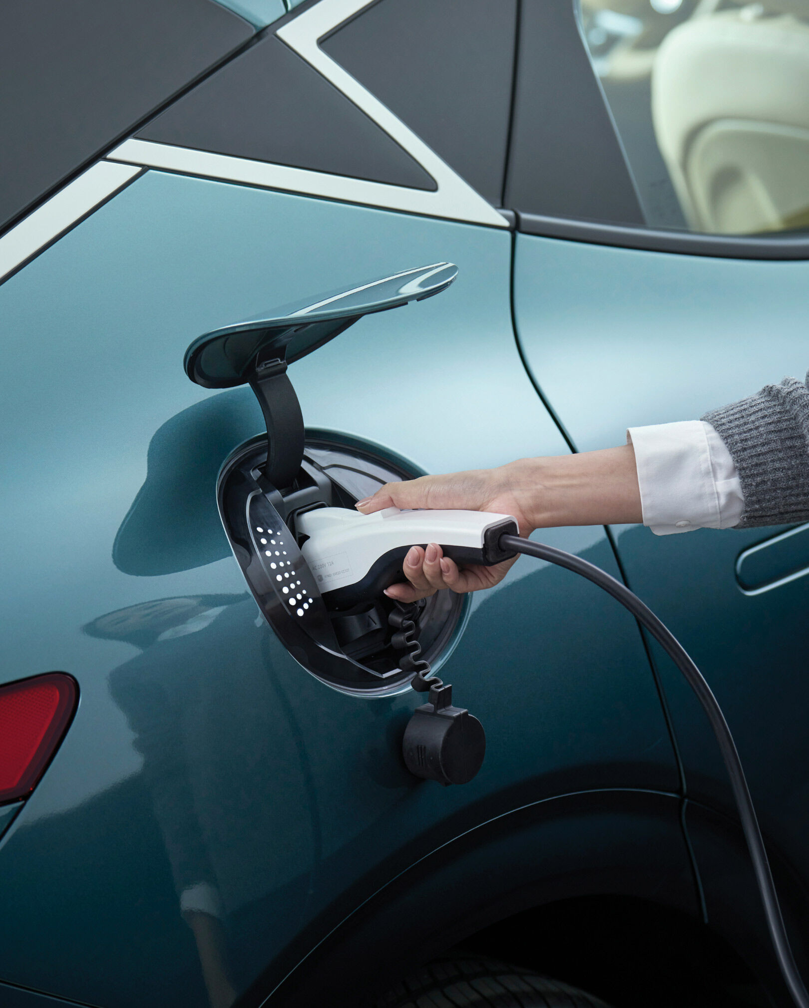 The Genesis car charger is open, and the hands of the person charging it appear to be enlarged.