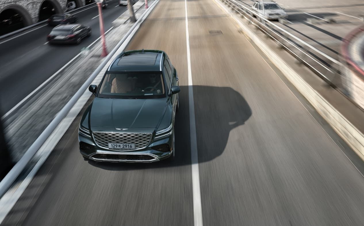The front of Storr Green GV80, driving fast on a two-lane road.