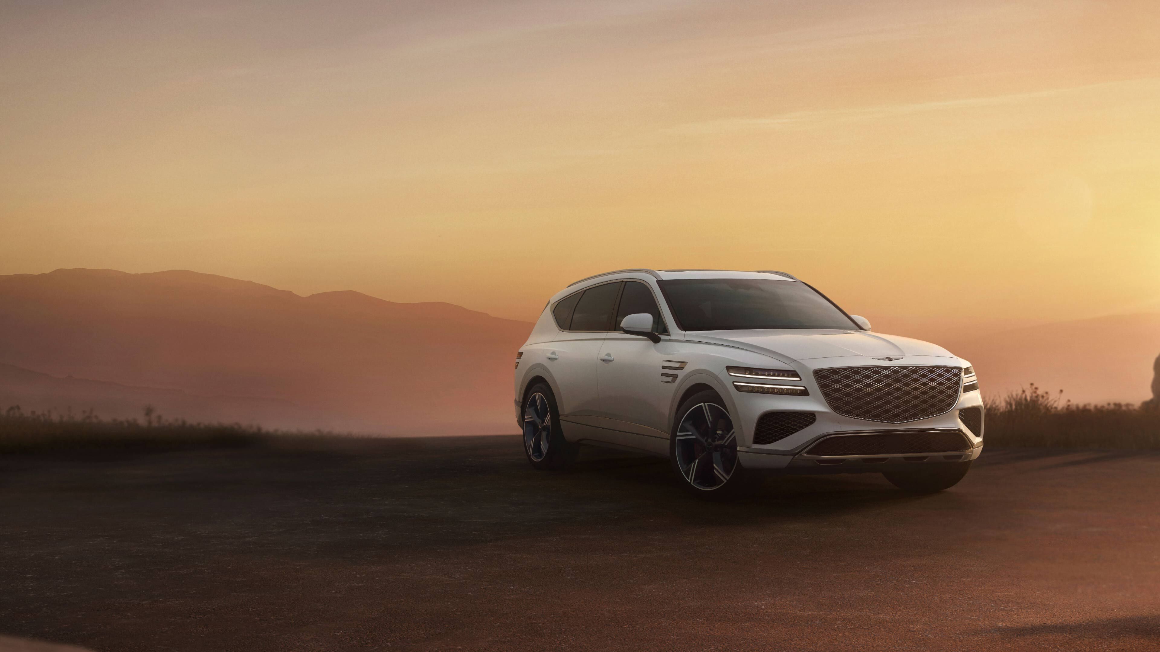 A white-toned GV80 is parked, displaying its front and side profiles against the backdrop of a vast, endless desert.