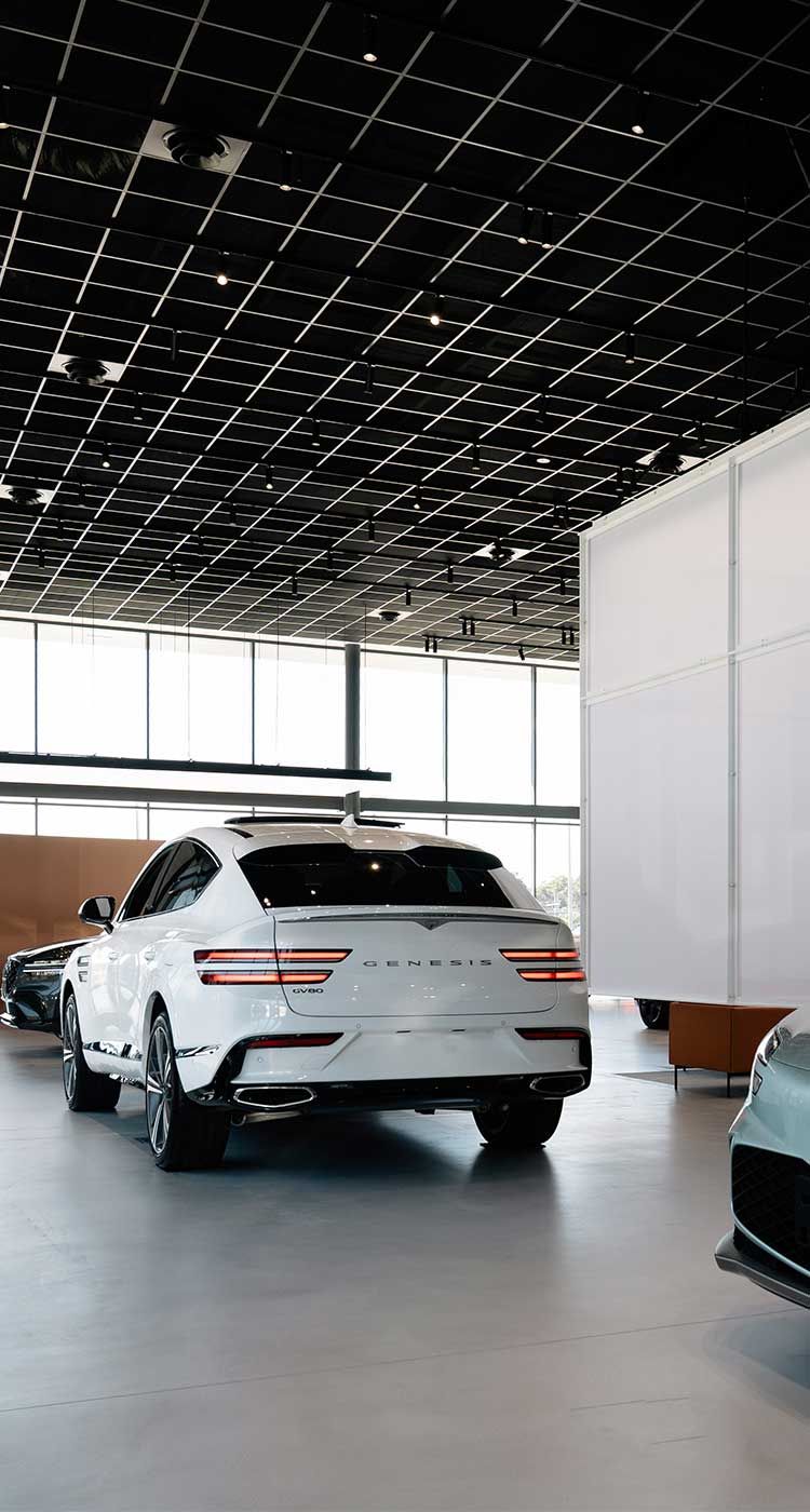 Genesis showroom interior featuring the GV60 and Electrified G80 electric vehicles set against a minimalist, light-filled space that highlights luxury, innovation, and sustainable design.