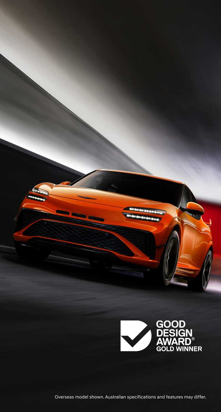 Genesis Magma performance SUV in vibrant orange driving through a dynamic tunnel, showcasing bold design and Good Design Award Gold Winner recognition.