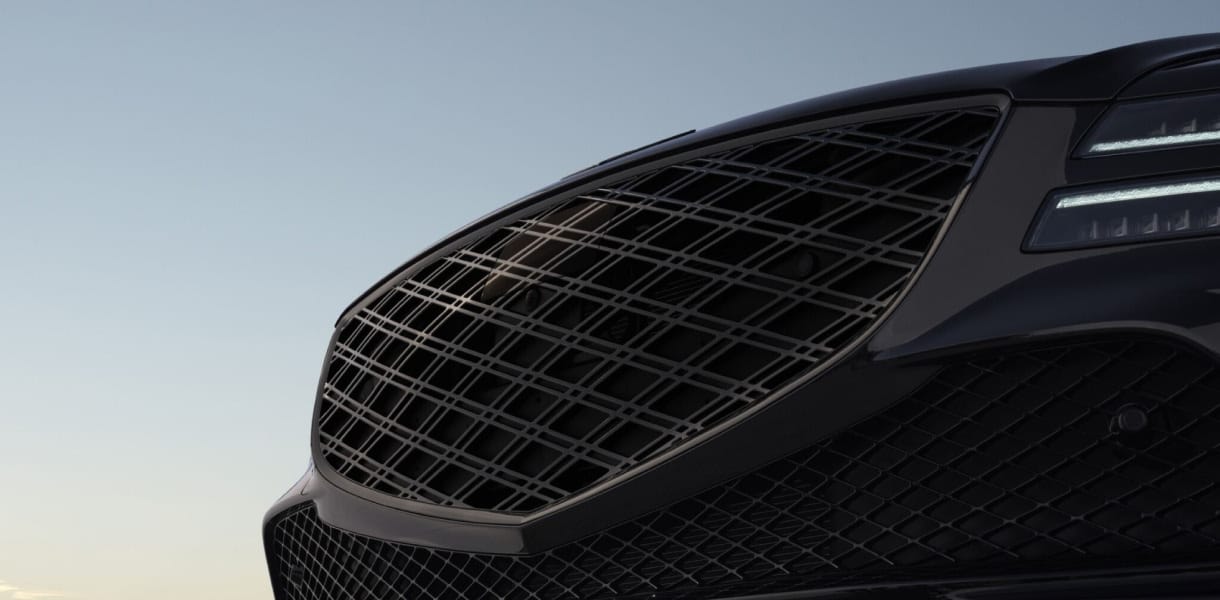 Close-up view of the Genesis G80’s front end, showcasing its bold grille and sleek headlights.