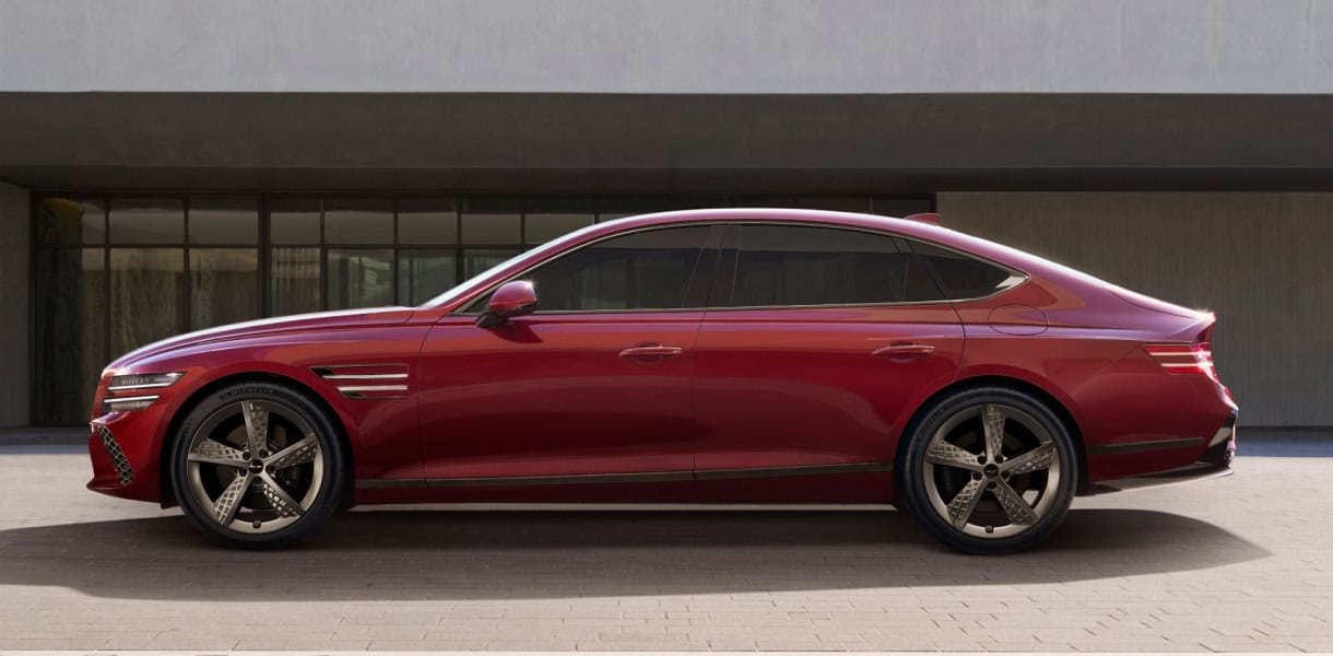 Genesis G80 luxury sedan in an elegant black finish, parked in front of a modern concrete backdrop.