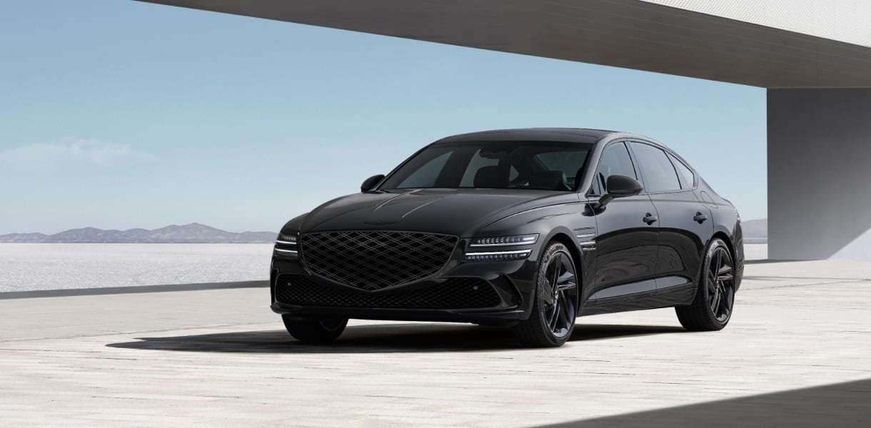 Genesis G80 luxury sedan in an elegant black finish, parked in front of a modern concrete backdrop.