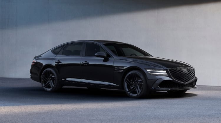 Genesis G80 luxury sedan in an elegant black finish, parked in front of a modern concrete backdrop.