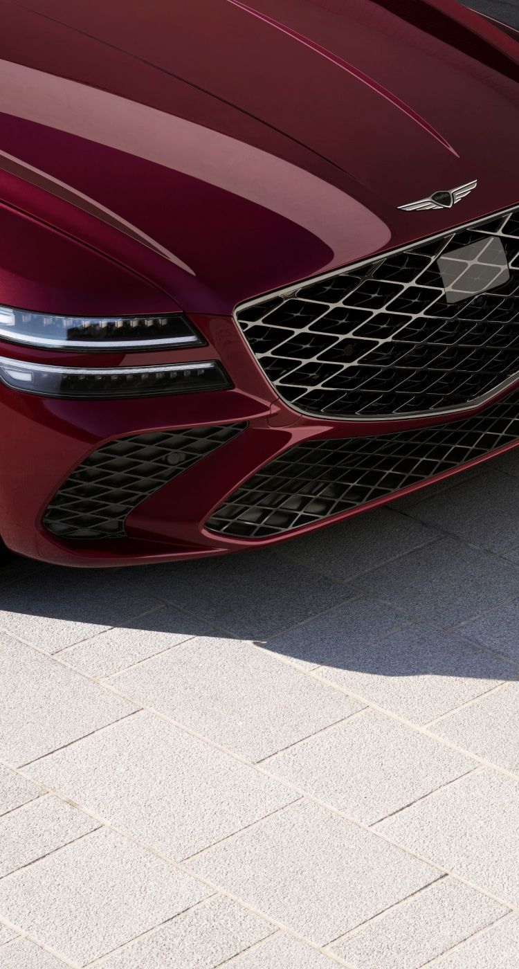 Close-up view of the Genesis G80’s front end, showcasing its bold grille, sleek headlights, and stylish alloy wheels.