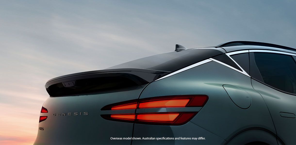 Rear view of a Genesis GV60 electric SUV in green, featuring distinctive dual-line LED tail lights, sculpted tailgate, sporty roof spoiler, and sleek coupe-inspired design. 