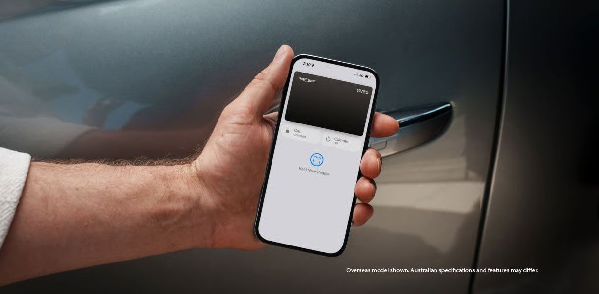 Hand holding smartphone using Genesis Digital Key near GV60 door handle, showcasing keyless entry technology and connected car features.