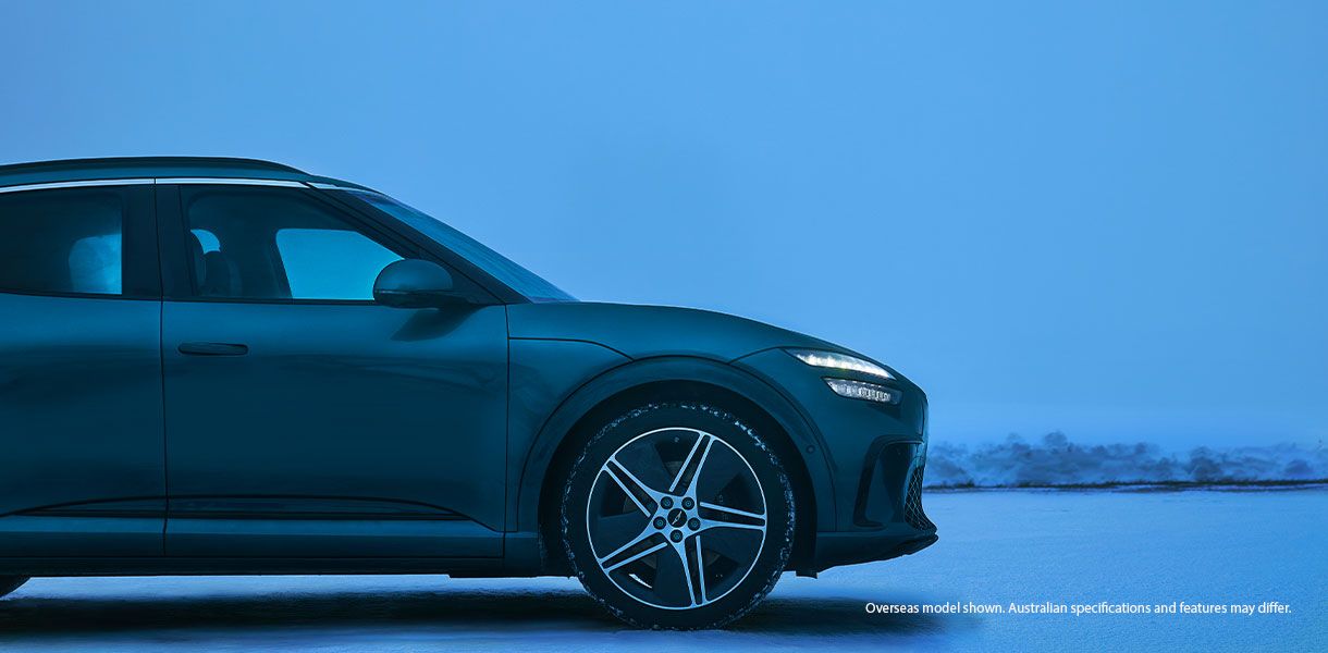 Genesis GV60 Advanced electric SUV parked on a snowy landscape with frozen lake and a snowy mountain in the background