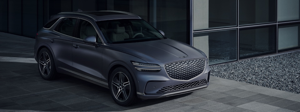 Silver GV70 showing the left side side profile in a dark gravel terrain with a rocky mountainous background in low lighting