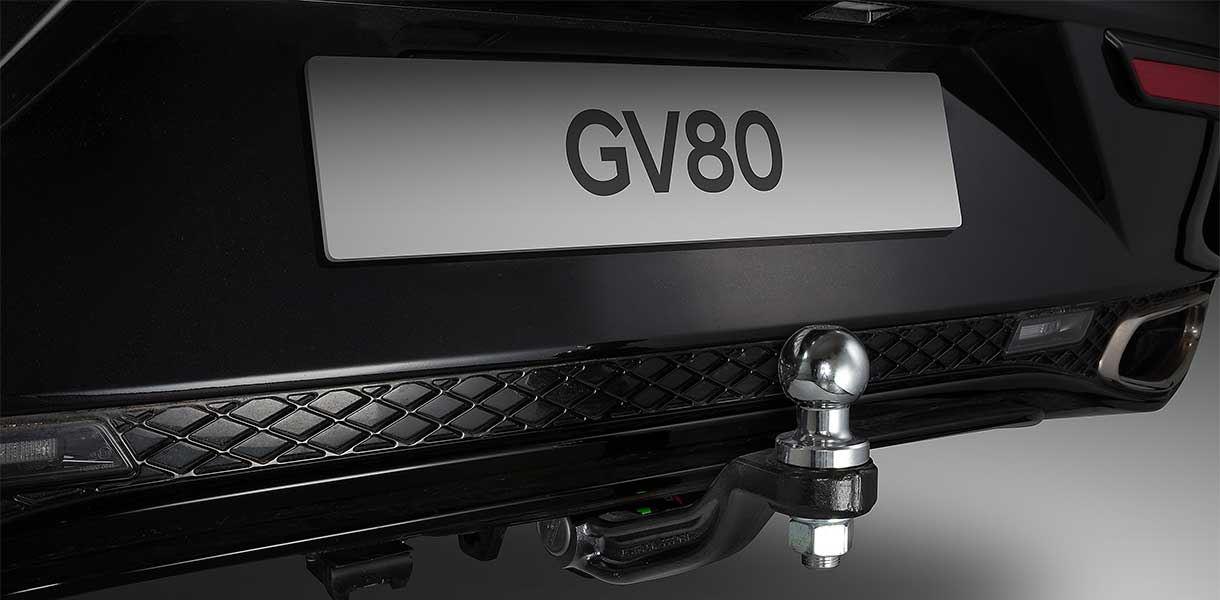 Close-up of the rear of a Genesis GV80 featuring a towball and wiring harness, showcasing the vehicle's towing capabilities and premium exterior detailing.