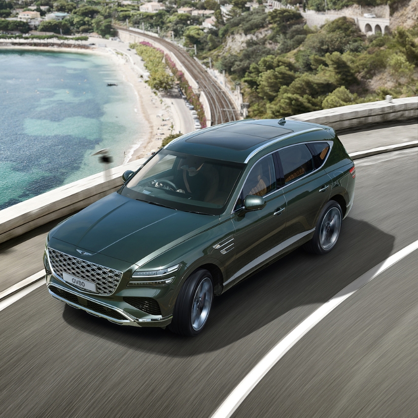 green gv80 front view driving across city lanscape