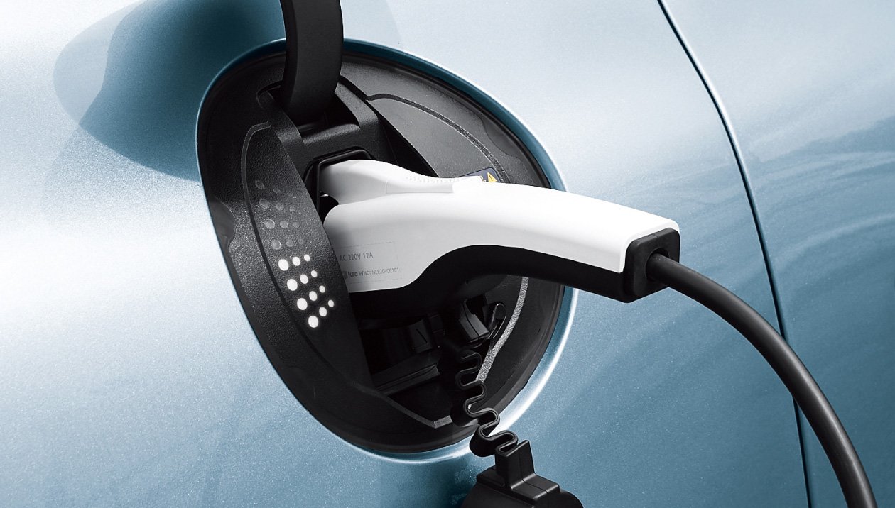 An electric charging plug sits in a lime green Genesis, futuristic LEDs light up to indicate the charging level