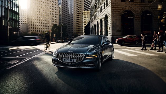 An aerodynamic executive saloon drives through the business district on a sunny afternoon 