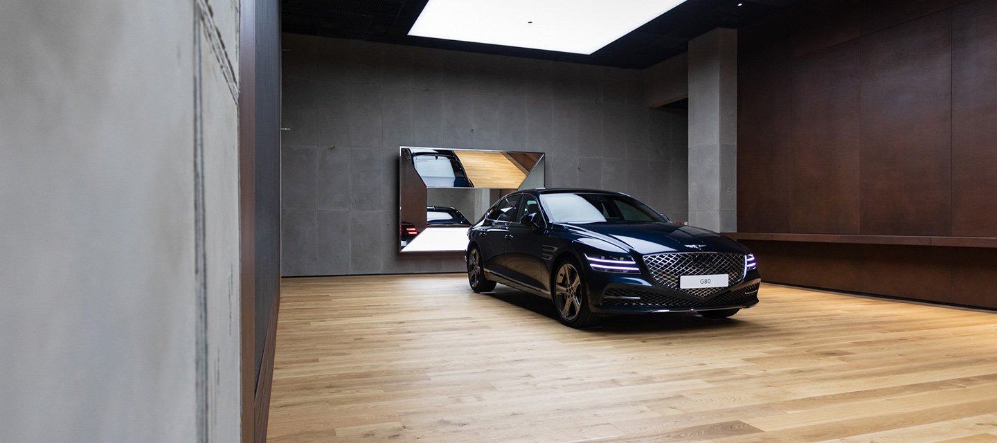 Ein ruhig wirkendes Studio mit hellem Holzfussboden, schmeichelhafter Deckenbeleuchtung und zwei funkelnden Autos in der Auslage