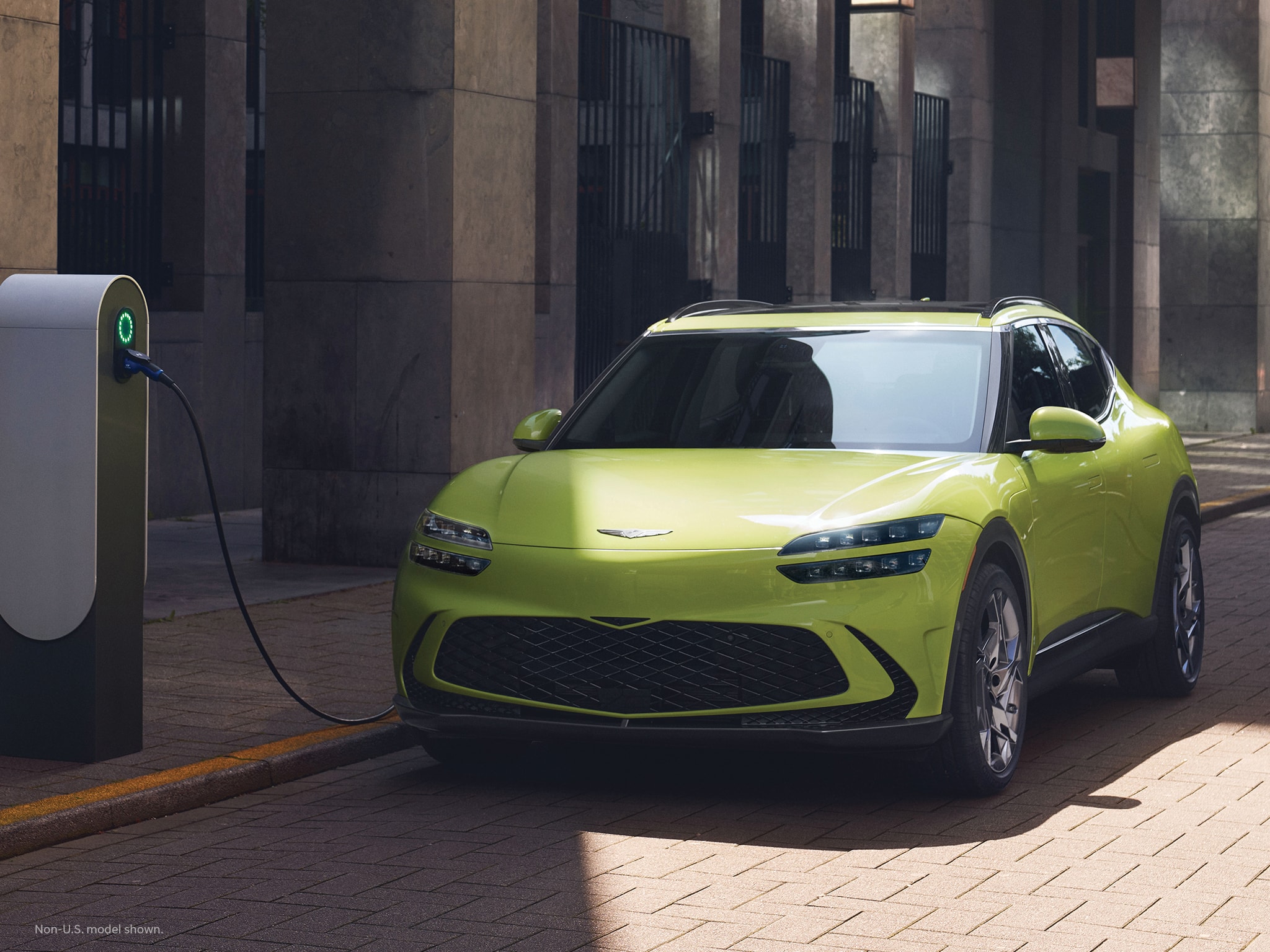 2023 Genesis GV60 shown in Sao Paulo Lime at an electric charging station.