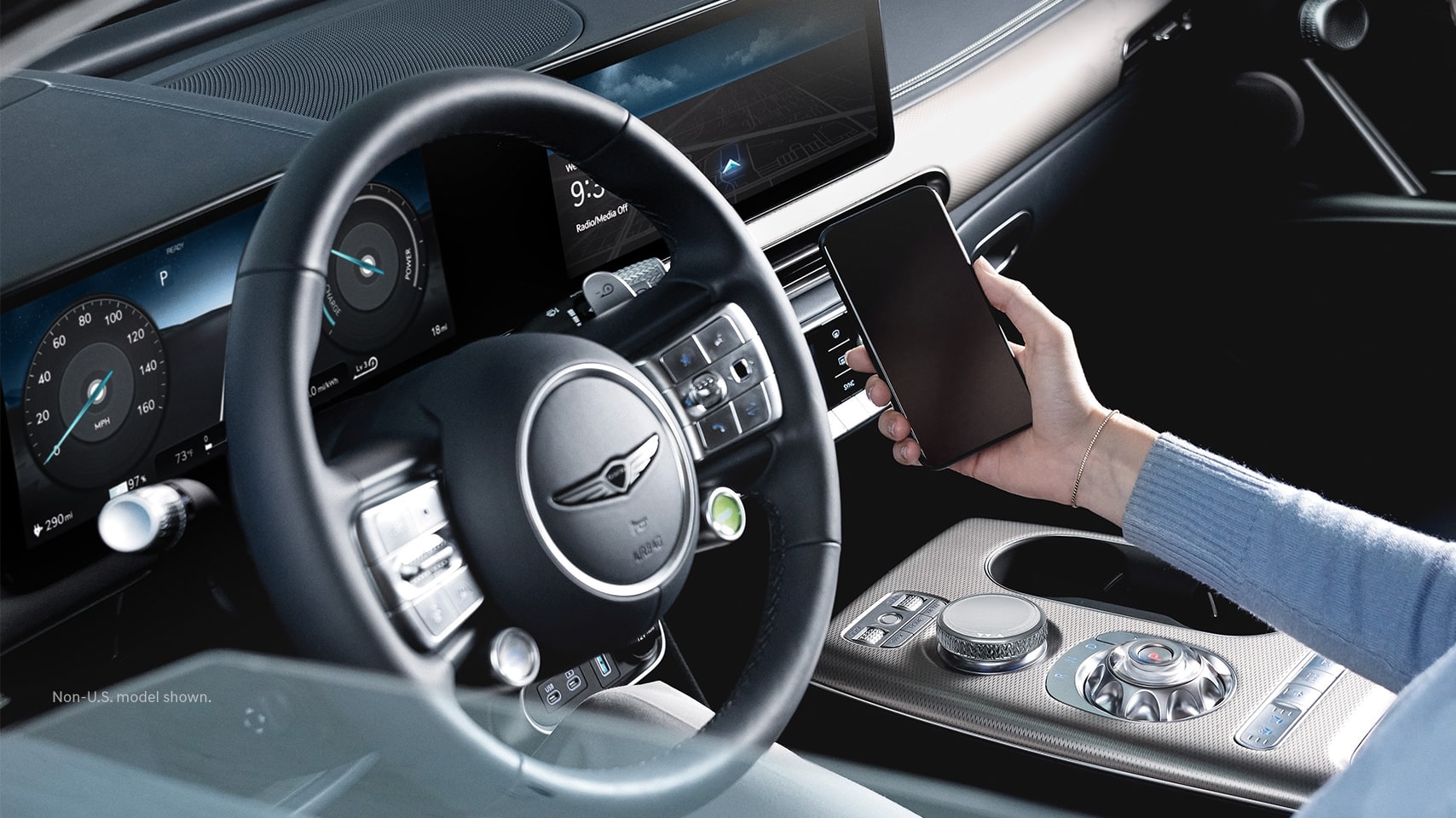 2023 Genesis GV60 interior with driver connecting smartphone. 