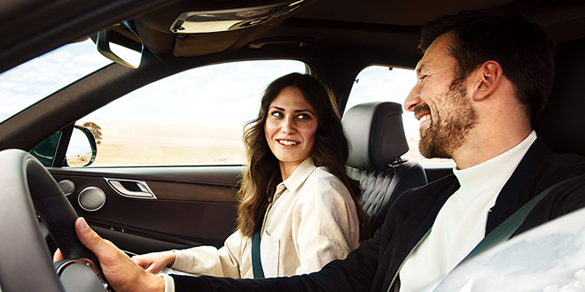 happy couple in a genesis car smiling.