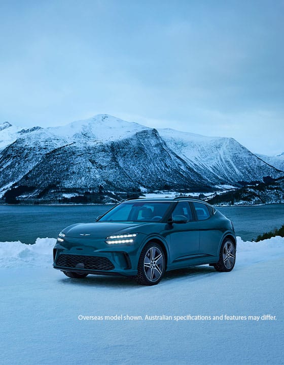 Genesis GV60 Advanced electric SUV parked on a snowy landscape with mountains and a frozen lake in the background