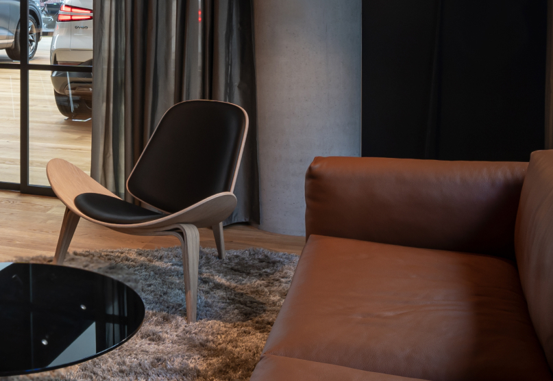 The consultation room has a brown sofa, circle table, and wooden chair.