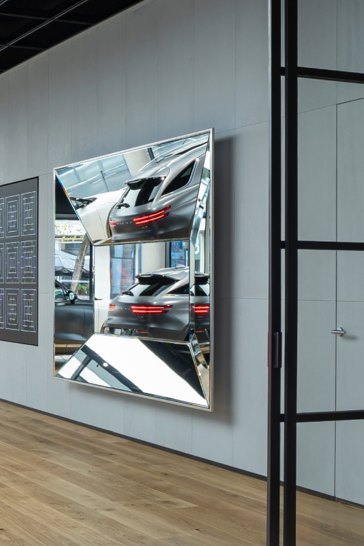 A polyhedral mirror and LED drawing of a Korean traditional pattern hang on the wall.