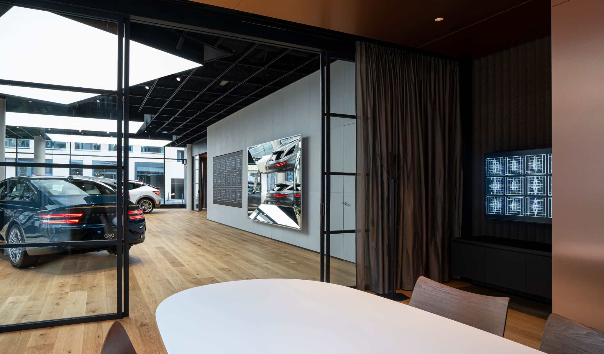 'Genesis vehicles are seen through the consultation room's glass door. Next to them are a polyhedral mirror and an LED drawing of Korean traditional patterns.
