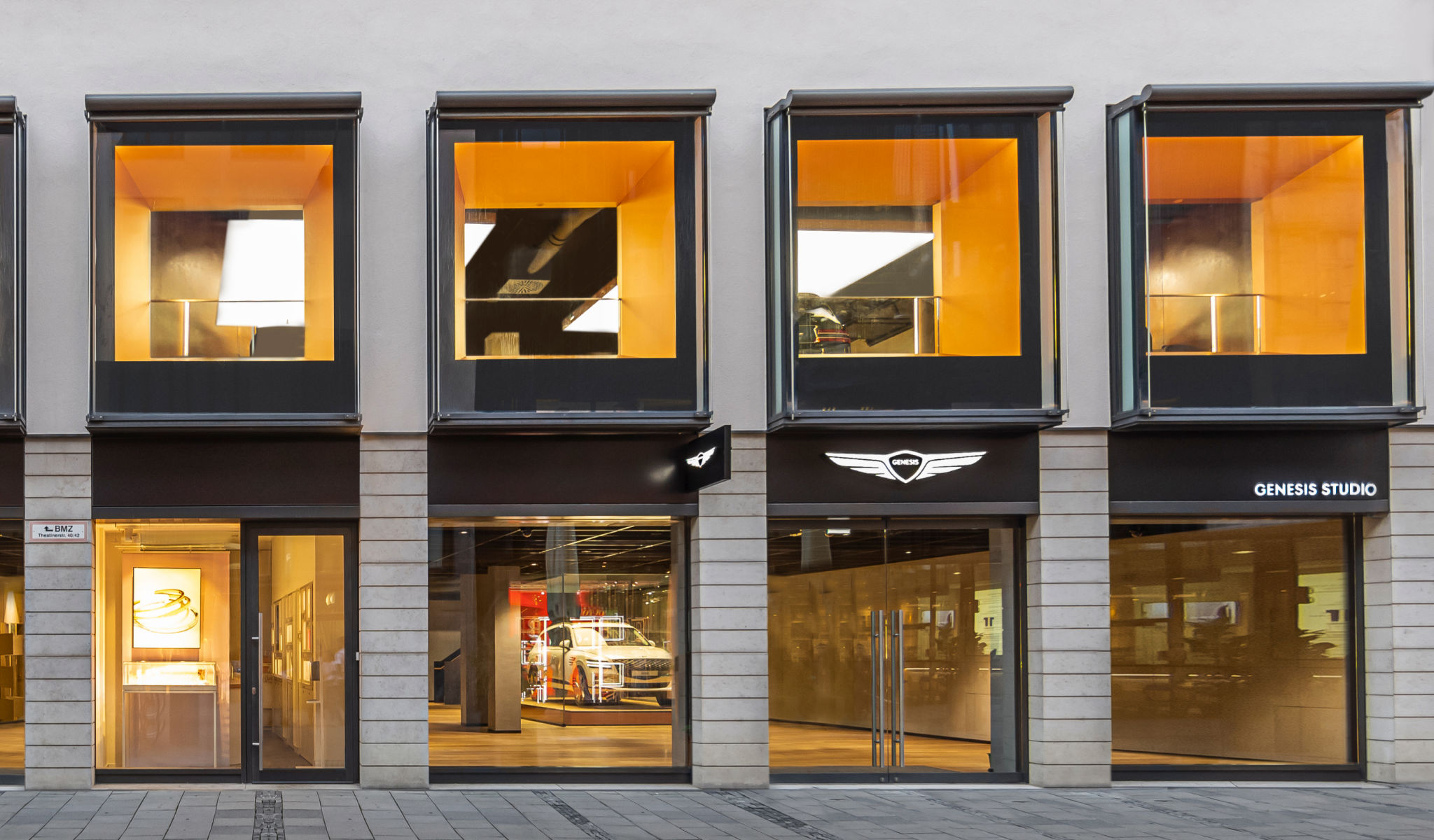 An exterior view of a Genesis space on the first floor. Genesis vehicles are seen on display through the floor-to-ceiling windows.